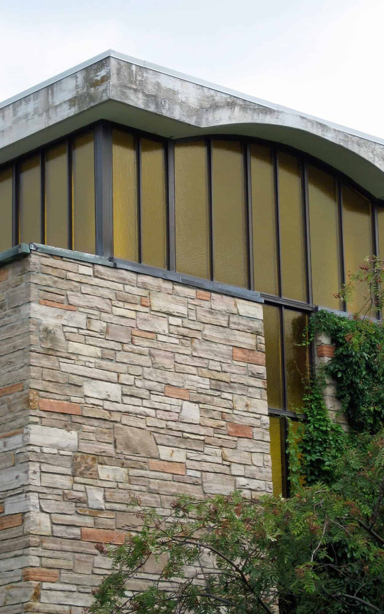 Corner detail of the chapel with its floating concrete roof amber clerestory windows and quarry faced sandstone walls