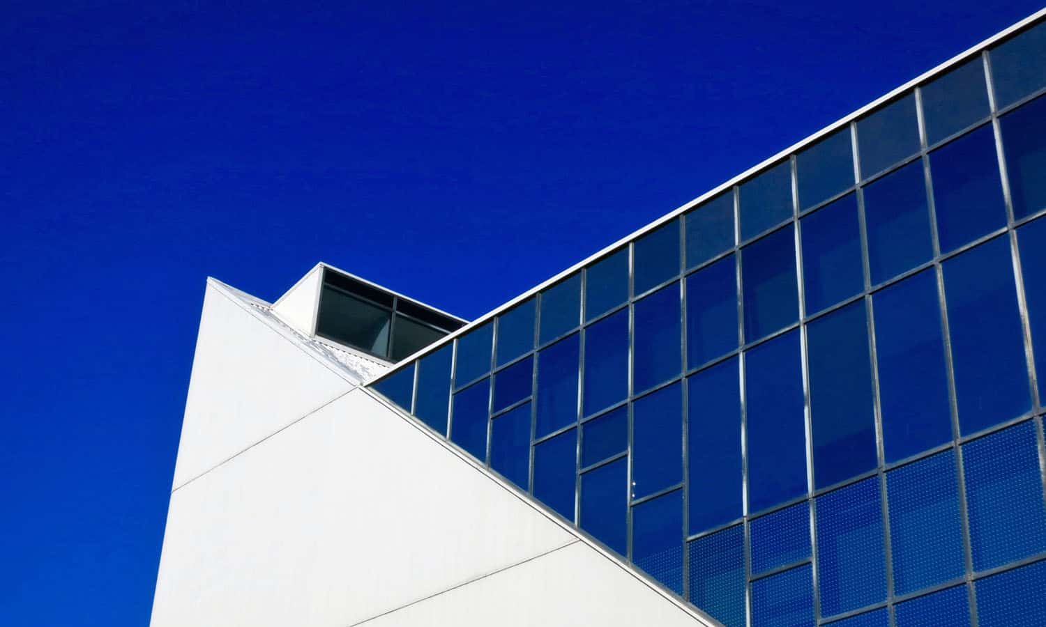 The white finish of the aluminum siding contrasts with the dark reflective glass and black anodized mullions (now faded)