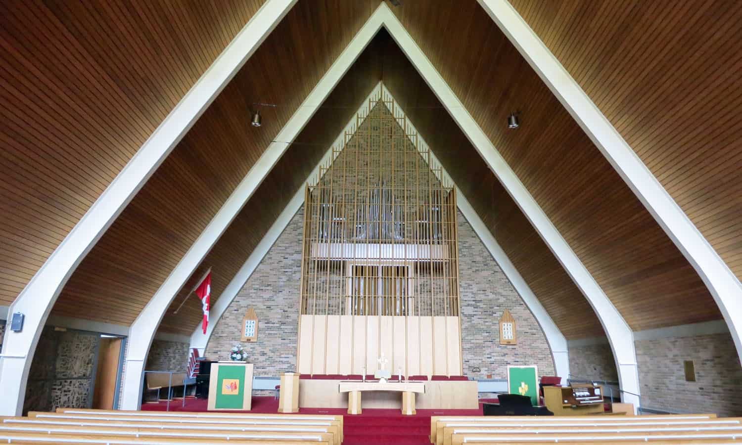 The interior of the sanctuary with its steel arches, wood ceiling, and brick walls and decorative organ screen